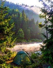 Misty mountain morning, camping tent nestled by a river. Lush forest surrounds