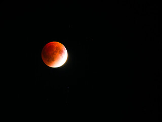 A red moon during a lunar eclipse occurs when Earth blocks direct sunlight, and the Moon is illuminated by sunlight filtered and refracted through Earth’s atmosphere.