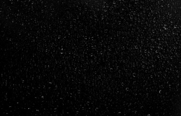 Fototapeta premium Black and white photo of rain drops on a glass window creating abstract texture and moody atmosphere.