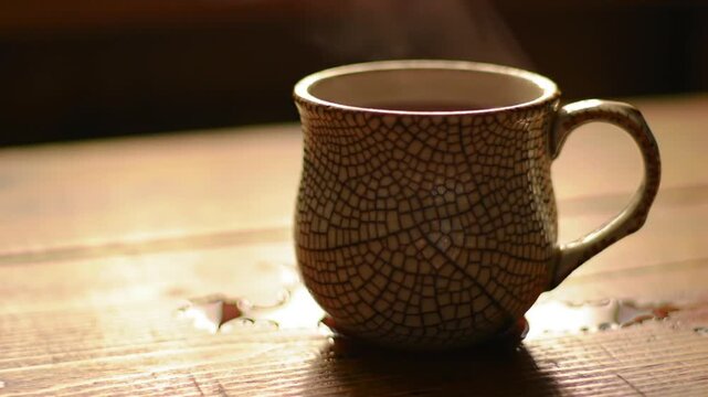Steaming mug of tea or coffee on a wooden table, warm beverage indoors