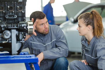mechanic teaching machine settings to young apprentice