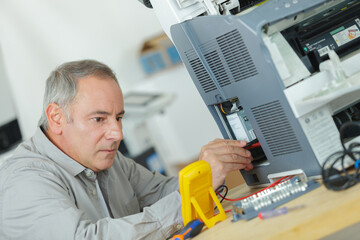 senior technician using multimeter to test electrical appliance