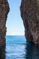 Scenic view of the sea through a rocky passage with turquoise water and clear blue sky.