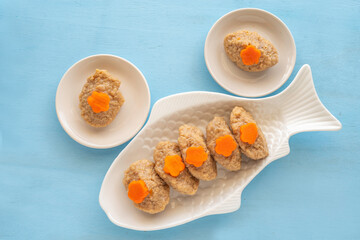 Gefilte fish served with carrots on traditional platter over blue wooden background. Top view.
