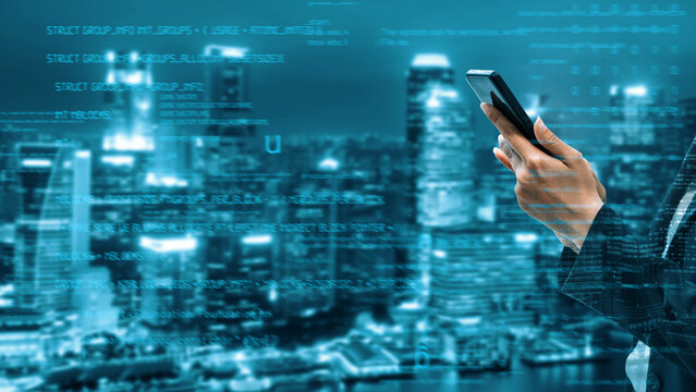 A person holds a smartphone in front of a modern city skyline illuminated by night, overlaid with digital data visualizations symbolizing connectivity and technology. Xenic