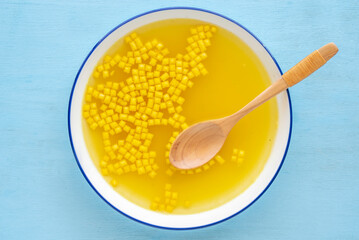 Bowl of chicken broth served with mini croutons on blue wooden background. Top view.
