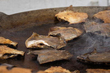 Cooking flounder on the hot pan. Fried flounder - traditional seafood - on large frying pan at  fair. 