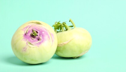 Two kohlrabi vegetables on a mint green background
