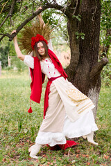 Obraz premium A beautiful woman in a national Ukrainian costume with a wreath of red flowers and wheat ears is posing near a tree in the forest, embodying the spirit of Ukraine and its rich cultural heritage .