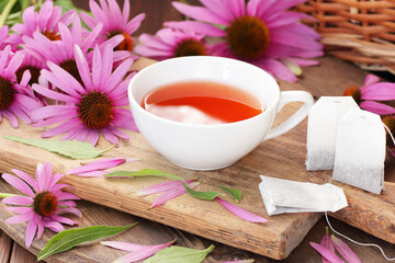 Echinacea purpurea herbal tea and plant flowers with paper tea bags on rustic background, copy space, natural medicine, antiviral treatment, immune booster concept
