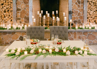 Elegant dining setup with candles and greenery in a cozy rustic venue for a special celebration event