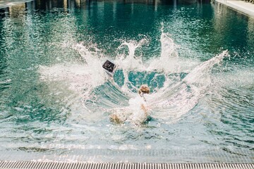 Businessman dropping laptop in swimming pool during summer vacation