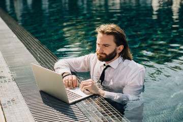 Businessman working on laptop in swimming pool