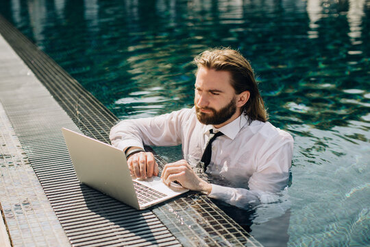 Businessman working on laptop in swimming pool