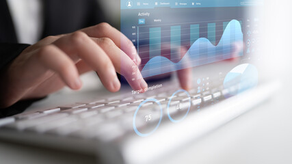 A businessperson engages with data analysis using a keyboard while viewing transparent graphs. The image showcases modern technology in a professional setting. Impute