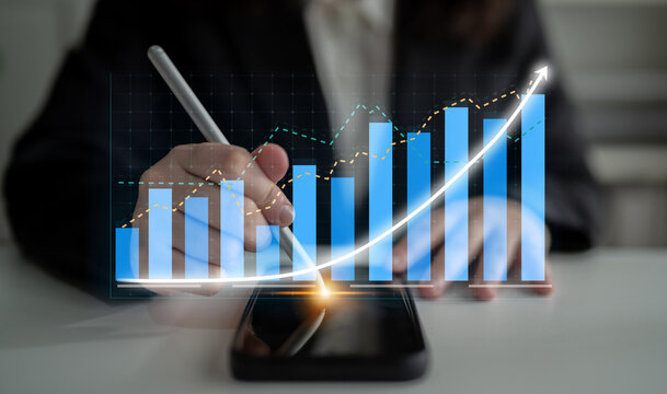 A business professional engages in financial analysis using a smartphone and digital chart, emphasizing growth trends and strategic planning in a modern workspace. Impute