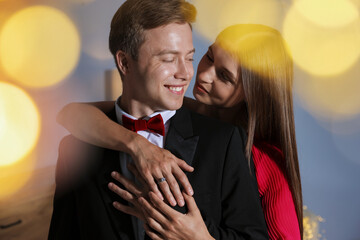 Making marriage proposal. Woman with engagement ring and her smiling fiance hugging at home. Bokeh effect