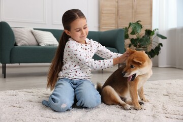 Cute little girl with her dog on floor at home. Child and pet