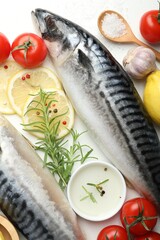 Fresh raw mackerels and spices on white table, flat lay. Seafood delicacies