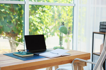 Home workplace. Laptop and stationery on wooden table