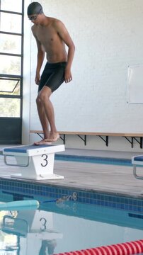 Vertical video: Swimmer approaching block 3, placing foot, crouching and bracing for launch