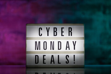 A cinematic lightbox with the words Cyber Monday Deals illuminated, placed against a rustic brick...