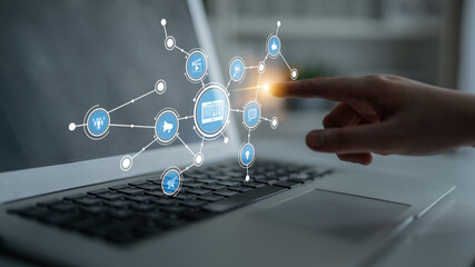 A person using a laptop interacts with a digital interface showcasing various icons representing...