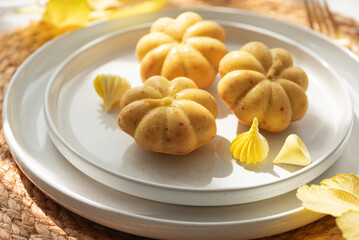 Pumpkin-Shaped Mini Cakes with Cream and Autumn Decor on Woven Placemat