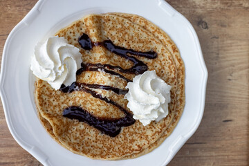 Delicious golden pancakes with rich chocolate, whipped cream and creamy ice cream topping. Top view.