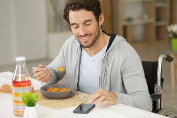 disabled young man having lunch and using phone