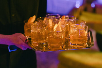 Bartender serves cocktails on a tray at an evening social event in a vibrant lounge setting