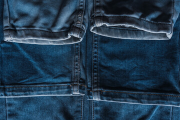 Naklejka premium A close-up stack of blue denim jeans with visible pocket textures and seam details.