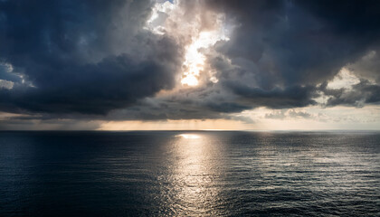 A Radiant Light Pierces Through Dark Clouds Reflecting On A Tranquil Ocean Surface Creating A Serene And Mystical Atmosphere