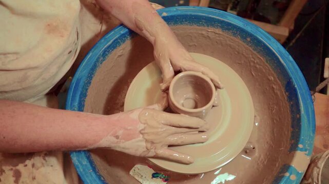 Potter creating small ceramic cup on pottery wheel