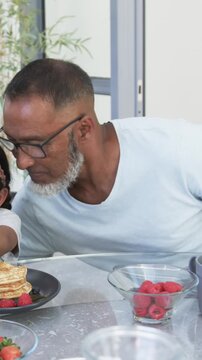 Vertical video: Opening shot showing father leaning in kissing girl while guiding pancake to mouth