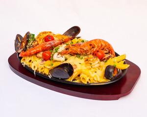 Appetizing seafood pasta served on a cast iron plate with a red board, garnished with shrimp and mussels, set against a white background.