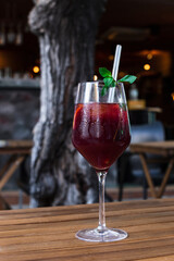 A beautiful glass of Spanish sangria on an outdoor café table, with a blurred bar and tree in the background