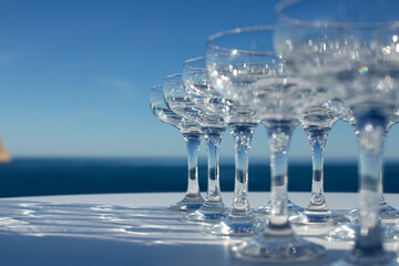 Empty champagne glasses close-up on a white table with the blue sea in the background, catering 
