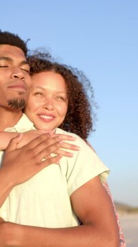 Vertical video: Couple wrapping arms around each other on beach while soaking golden sunset light