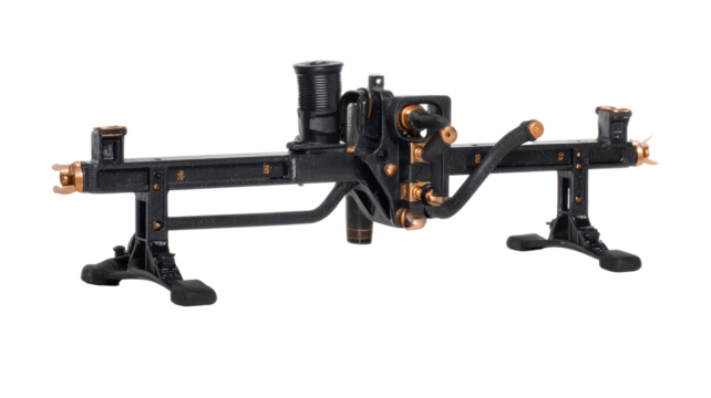 Dark, intricate mechanical device with brass accents,  mounted on support bases