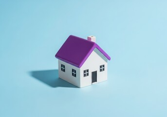 A small, simple toy house with a purple roof sits on a blue background with a shadow
