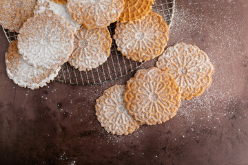 Top View of Pizzelles on a Wire Cooling Rack on a Cookie Sheet Sprinkled with Powdered Sugar