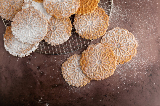 Top View of Pizzelles on a Wire Cooling Rack on a Cookie Sheet Sprinkled with Powdered Sugar