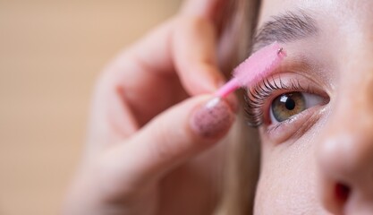 Caucasian woman brushing her eyelashes after lamination. 