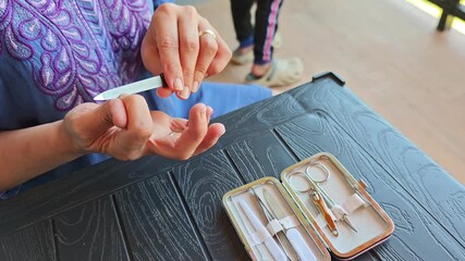 Professional beautician performing precise nail care routine, carefully filing and grooming fingernails with specialized manicure tools at home setting