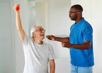 Doctor or nurse or physiotherapist caregiver exercise with senior man at clinic or nursing home