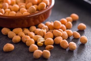 Peanuts in a crispy crust on black table.