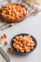 Peanuts in a crispy crust in bowl on white table.
