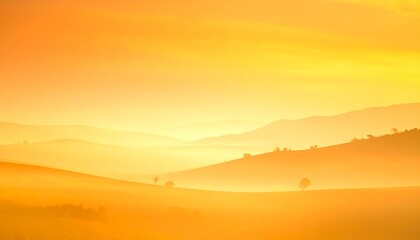 Obraz premium Golden-orange misty landscape with rolling hills, scattered trees, and fading mountain ridges