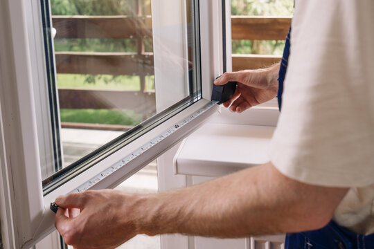 Repairman measures PVC window frame for home installation